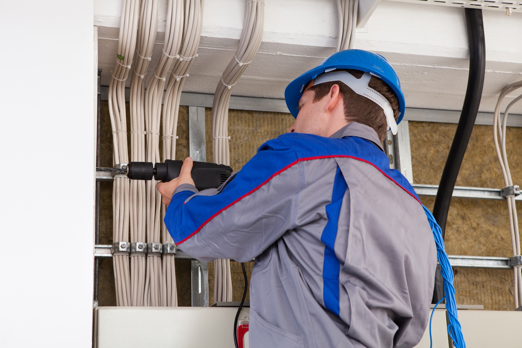 Male worker with electric drill working in office